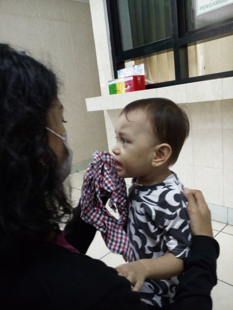 Ini saya lagi mendiamkan Kriby nangis di Puskesmas. Saya kalau anak nangis emang cool begitu. Saya jadi terlihat begitu keibuan ya. (mana keliahatan mukanya. Orang ketutup rambut semua!)